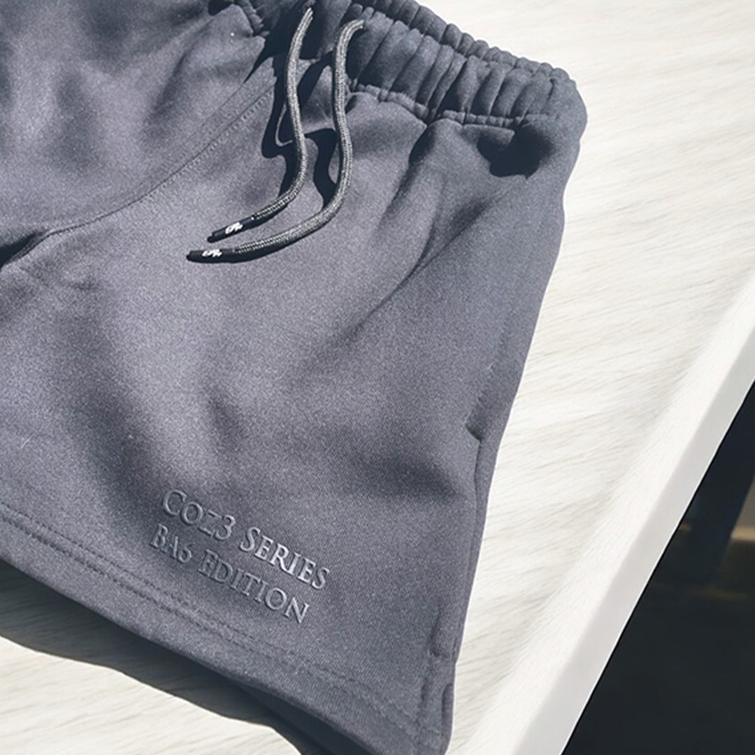 An array of Coz3 Ba6 Edition Shorts in various colors including pink, blue, purple, white, and gray, displayed in a line with a soft focus background. The shorts are characterized by a relaxed fit, 3-inch waistband, and drawstrings.