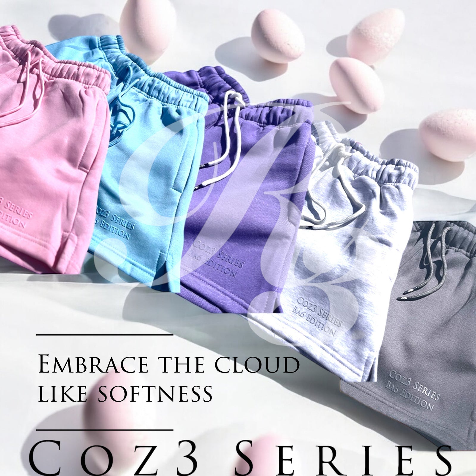 An array of Coz3 Ba6 Edition Shorts in various colors including pink, blue, purple, white, and gray, displayed in a line with a soft focus background. The shorts are characterized by a relaxed fit, 3-inch waistband, and drawstrings.