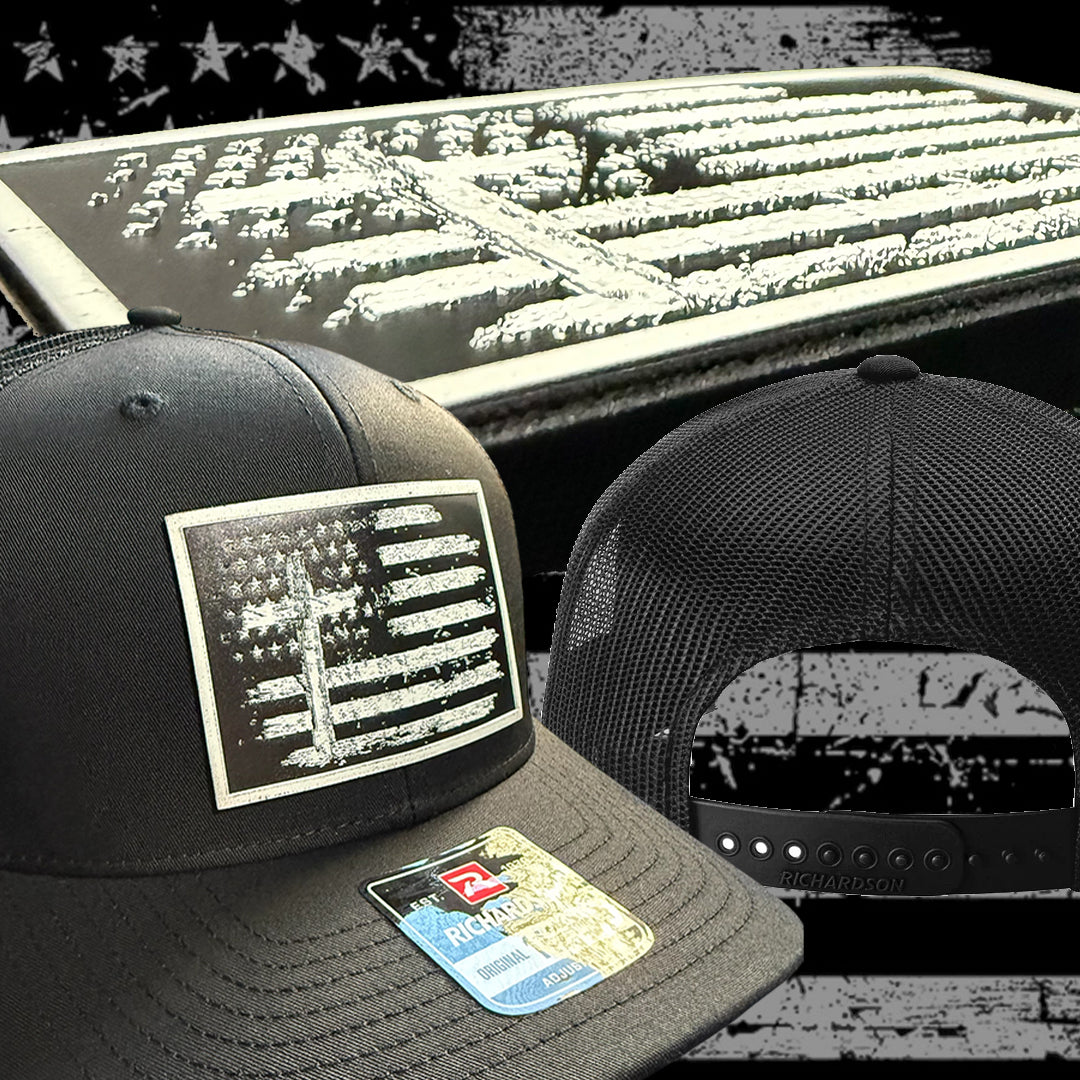 Two black baseball caps with American flag and cross design on a textured surface.