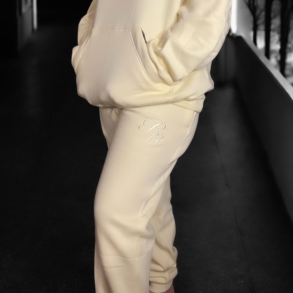 A close-up of a person wearing gray Coz3 Max Unisex Sweatpants, showing the side pocket and the brand&#39;s logo on the leg of the pants.