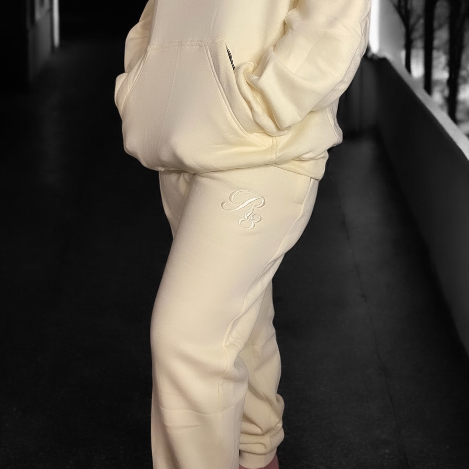 A close-up of a person wearing gray Coz3 Max Unisex Sweatpants, showing the side pocket and the brand's logo on the leg of the pants.