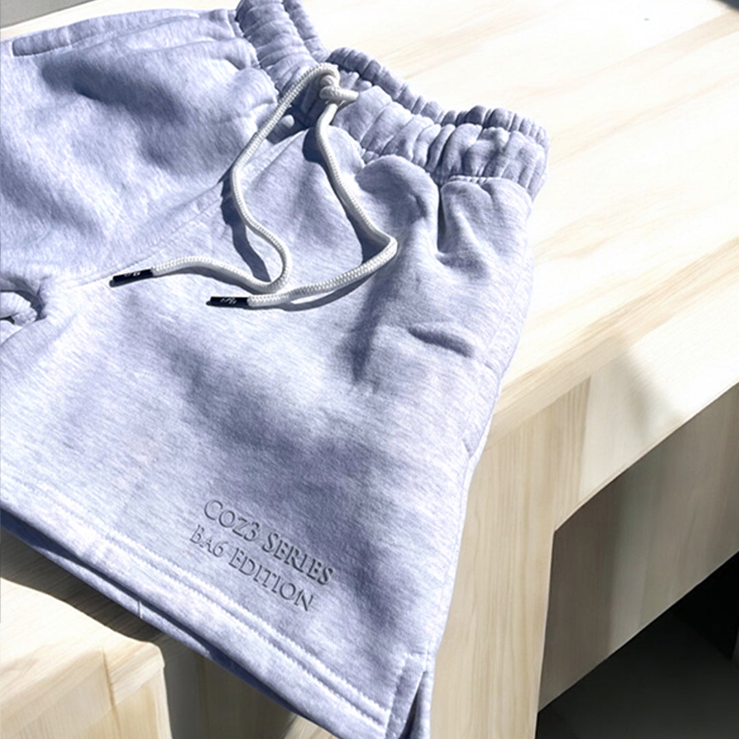 An array of Coz3 Ba6 Edition Shorts in various colors including pink, blue, purple, white, and gray, displayed in a line with a soft focus background. The shorts are characterized by a relaxed fit, 3-inch waistband, and drawstrings.