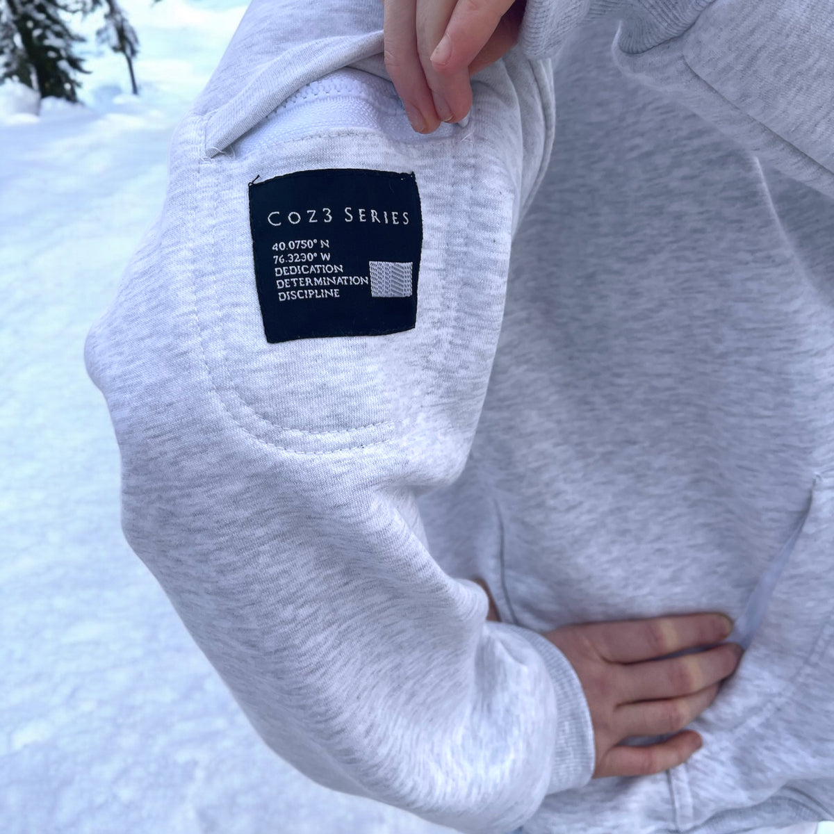 Person Standing in white hoodie displaying a pocket on the sleeve