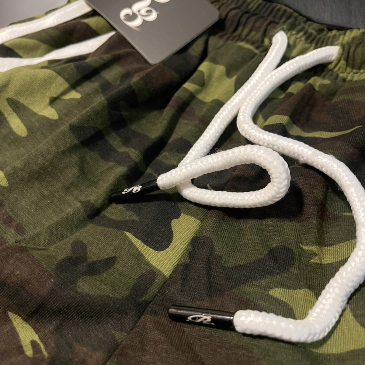 Lazer engraved logo on the string tips of camo colored yoga shorts