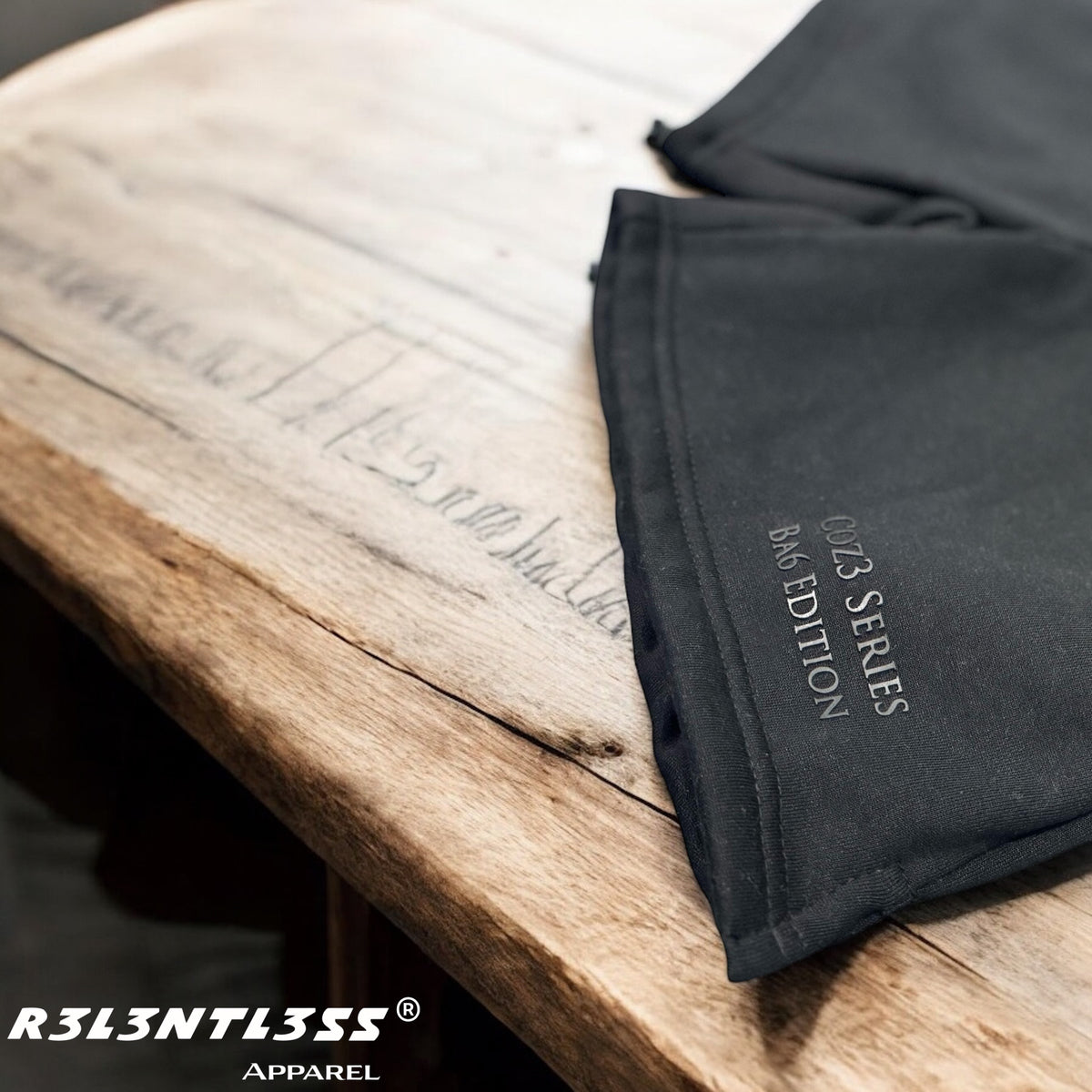 A pair of black Coz3 Ba6 Edition shorts with a drawstring waistband, displayed on a wooden surface.